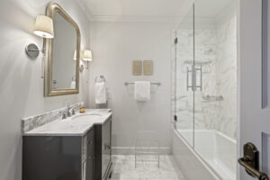 Narrow guest bathroom features compact yet elegant vanity and frameless shower.